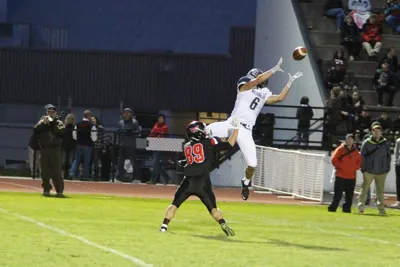 Elijah Benedick, Wilsonville No. 6 in a white jersey, leaping for a pass over a Mountain View defender in a black No. 89 jersey in the 2015 season opener at Mountain View
