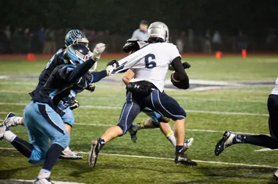 Elijah Benedick, Wilsonville No. 6 in a white jersey, running with the ball as Liberty defenders in navy and light blue chase him, in the 2015 5A quarterfinal at Liberty