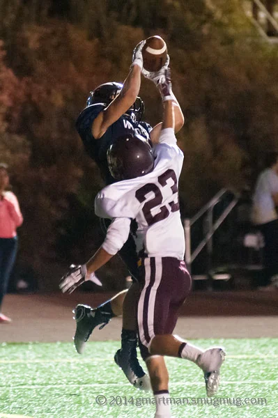 Elijah Benedick in a navy Wilsonville jersey catching a touchdown pass over a Milwaukie defender in a white No. 23 jersey, 2014