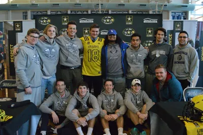 Draco Bynum in a yellow U.S. Army All-American No. 18 jersey with Wilsonville teammates in Wilsonville Football sweatshirts in front of a U.S. Army All-American Bowl backdrop