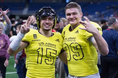 Draco Bynum in a yellow U.S. Army All-American No. 99 jersey posing on the field with Talanoa Hufanga, No. 15