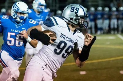 Draco Bynum, Wilsonville No. 99, running with the ball as a La Salle defender chases