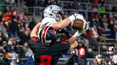 Nick Crowley, Wilsonville No. 3 in a white jersey and silver helmet, catching a pass over a Mountain View defender in a black No. 8 jersey in the 2024 5A state championship game
