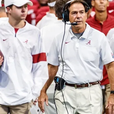 Anders Ericson on the Alabama sideline with head coach Nick Saban, football under his arm