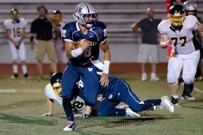 Johnny Ragin III, Wilsonville No. 28, carrying the ball past a fallen defender as opponents in white and gold pursue, 2012