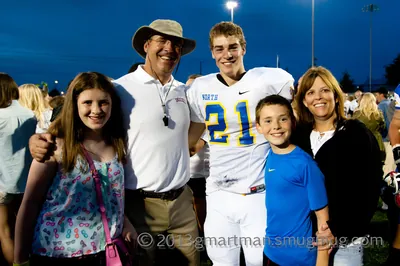 Tanner Shipley in a white North No. 21 jersey posing with family on the field at dusk after the 2013 Les Schwab Bowl