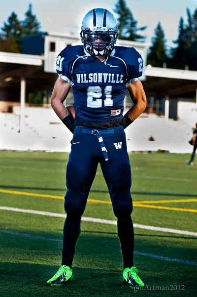 Posed portrait of Tanner Shipley standing on the field in his navy Wilsonville No. 21 uniform and silver helmet, 2012