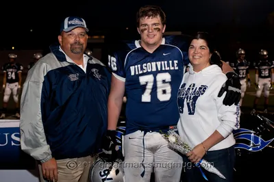 Andrew Walls in his navy Wilsonville No. 76 jersey posing on the field with family on senior night, 2011