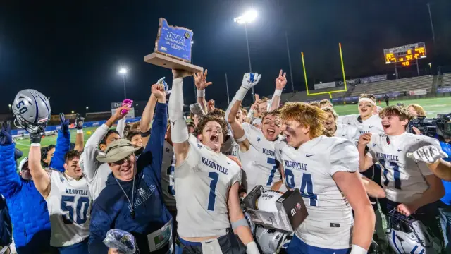 Wilsonville players raise the 5A state championship trophy